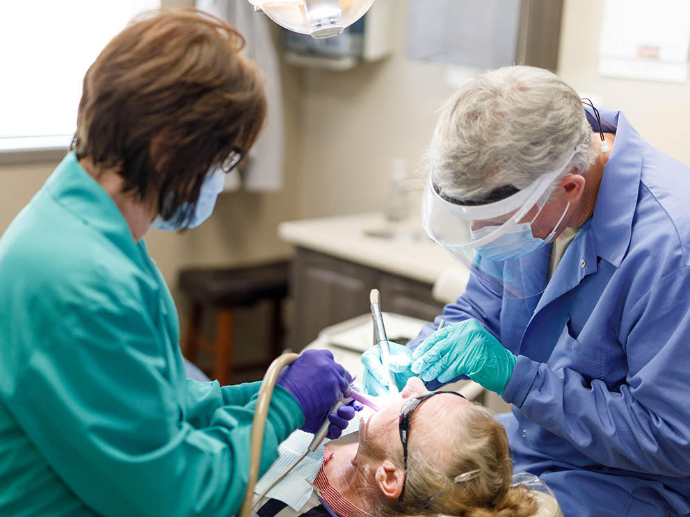 Patient receiving dental care from a dentist and a nurse.